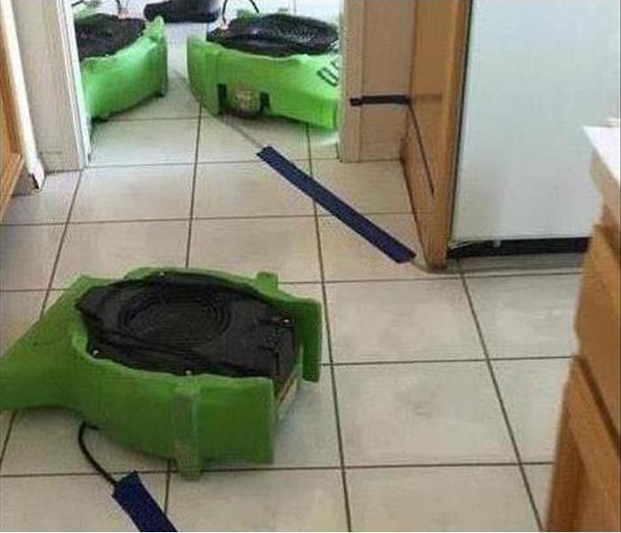Three air movers placed on a kitchen floor to dry out affected area by water