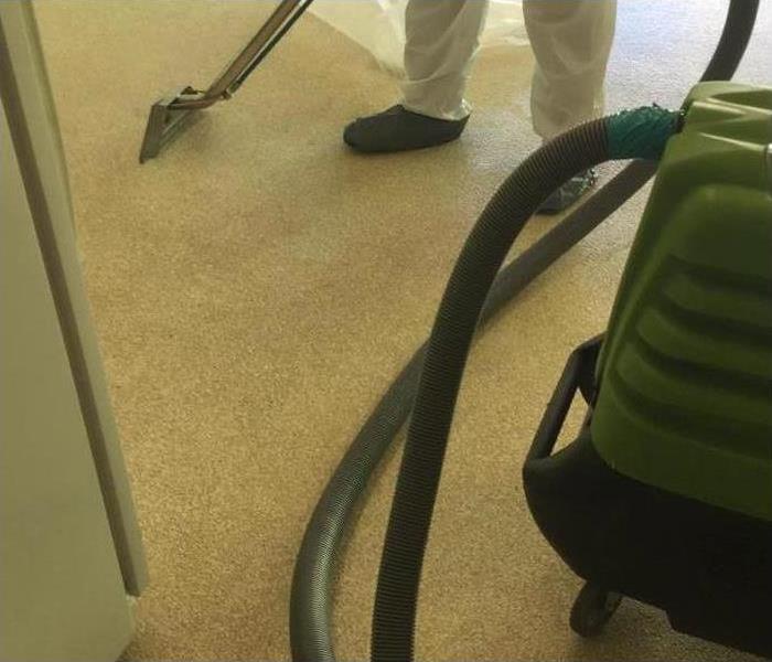 Someone extracting water with a vacuum to a carpet