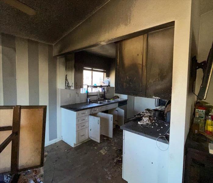 A kitchen with, soot, fire, and smoke damage.